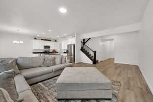 Living room featuring light wood finished floors, recessed lighting, stairway, and a chandelier