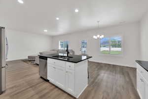 Kitchen featuring open floor plan, white cabinets, decorative light fixtures, recessed lighting, and stainless steel appliances