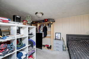 Bedroom featuring light carpet, a closet, and wooden walls