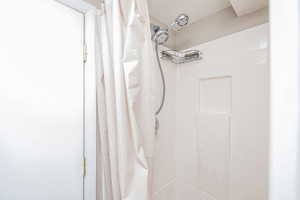 Bathroom view of a shower with shower curtain and a textured ceiling