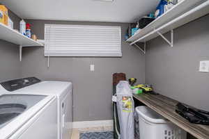 Laundry area featuring a textured wall, light tile patterned floors, and washer and dryer