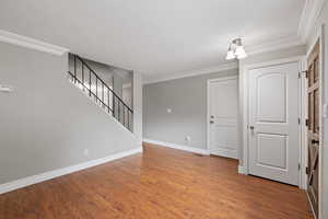 Front entry and living area featuring laminate flooring, two-tone paint and crown molding