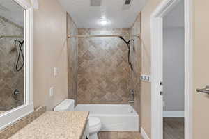 Primary bathroom featuring tile flooring, large vanity, and tiled tub/shower combination