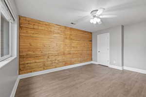 Primary bedroom featuring LVP flooring, two-tone paint, feature wall, and ceiling fan