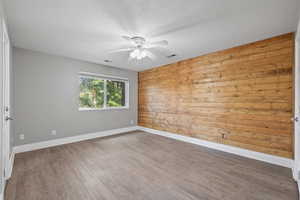 Primary bedroom featuring LVP flooring, two-tone paint, feature wall, and ceiling fan