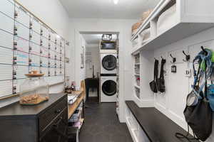 Mudroom featuring dark tile patterned flooring and stacked washer and clothes dryer