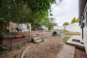 Fenced backyard featuring a garden and a storage unit