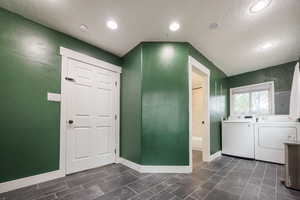 Washroom with a textured ceiling, washing machine and dryer, and recessed lighting
