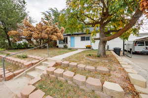 View of property hidden behind natural elements featuring a front lawn
