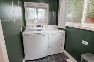 Laundry area with electric panel, washing machine and clothes dryer, and dark tile patterned flooring