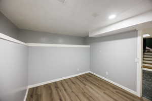 Finished below grade area featuring wood finished floors, stairway, and recessed lighting