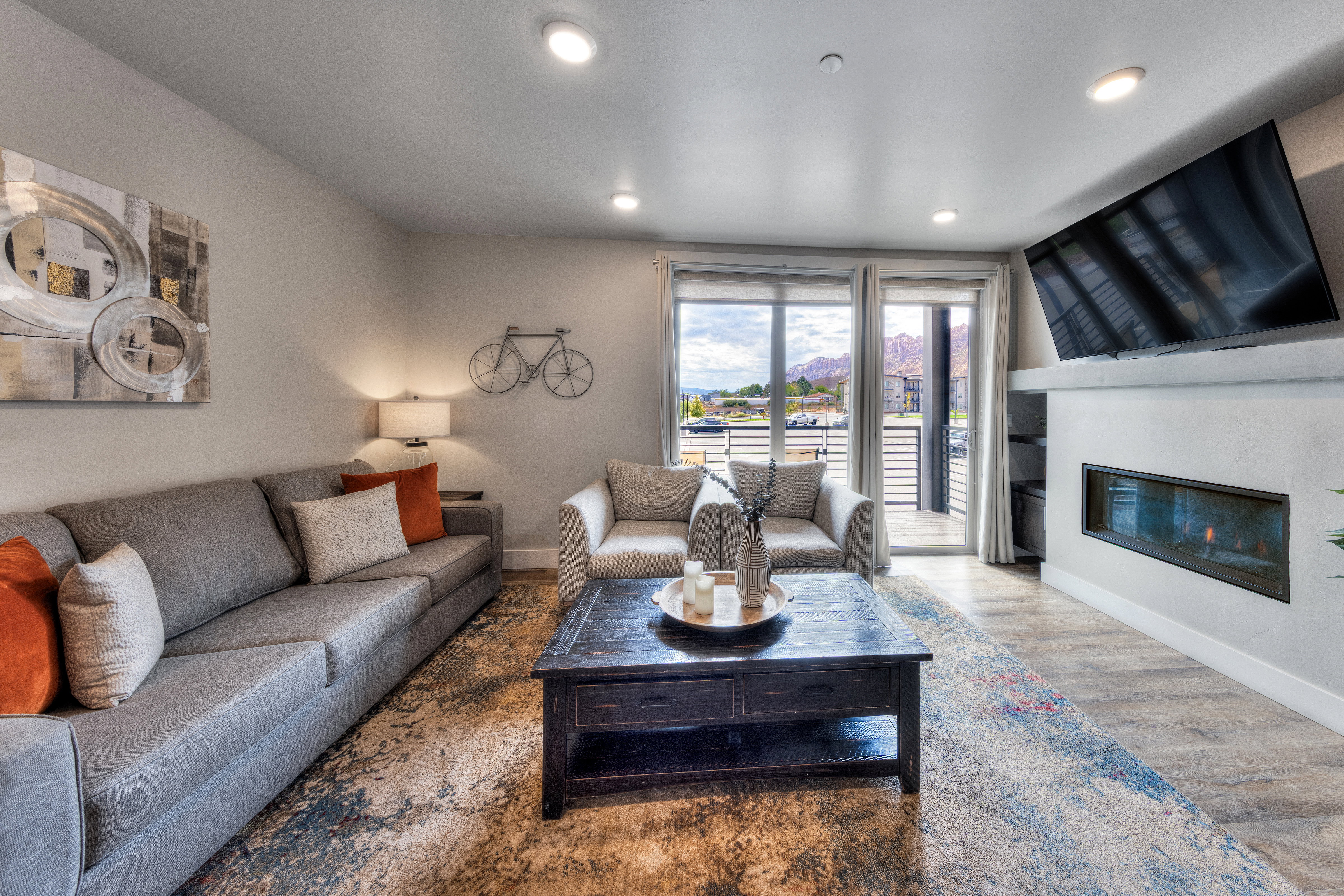 Living area with wood finished floors, a glass covered fireplace, and recessed lighting