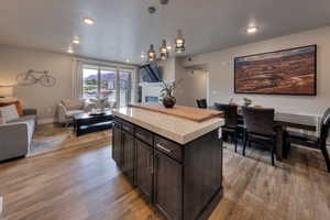 Kitchen featuring dark brown cabinets, open floor plan, decorative light fixtures, a center island, and dark wood-style floors