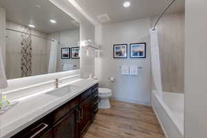 Bathroom with vanity, shower / bath combination with curtain, light wood-style flooring, and recessed lighting