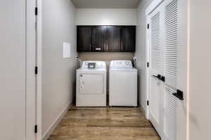 Washroom featuring cabinet space, light wood-style flooring, and washer and dryer