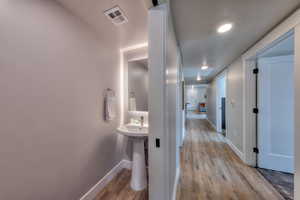 Corridor with light wood-style flooring and recessed lighting