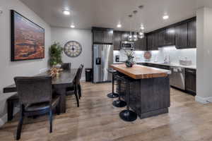 Kitchen with butcher block counters, decorative backsplash, stainless steel appliances, a kitchen breakfast bar, and a kitchen island