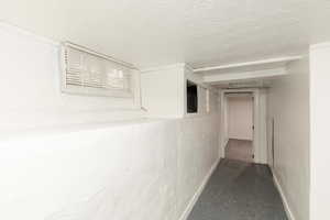 Hallway with a textured ceiling and light speckled floor