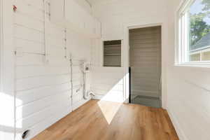 Laundry room with wood finished floors, wooden walls, and hookup for a washing machine