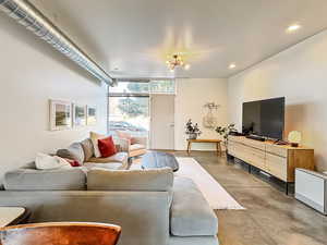 Living room with finished concrete floors, expansive windows, and recessed lighting