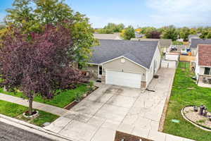 View of front of house featuring a shingled roof, concrete driveway, a front lawn, and a garage