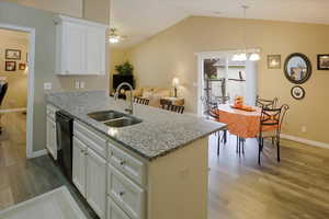 Kitchen with white cabinets, light stone countertops, light wood-type flooring, ceiling fan, and hanging light fixtures