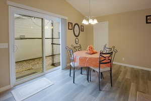 Dining space featuring light wood finished floors, vaulted ceiling, and a chandelier