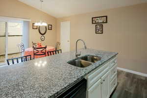 Kitchen with light stone countertops, pendant lighting, a chandelier, dark wood-style flooring, and white cabinetry