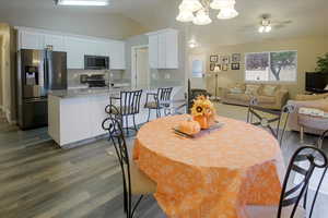 Dining space featuring lofted ceiling, dark wood-type flooring, a ceiling fan, and a chandelier