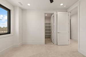 Unfurnished bedroom with a walk in closet, recessed lighting, light carpet, and a ceiling fan