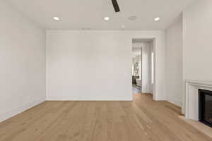 Unfurnished living room featuring recessed lighting, light wood-type flooring, ceiling fan, and a glass covered fireplace