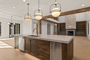 Kitchen with decorative light fixtures, an island with sink, open floor plan, light wood-type flooring, and recessed lighting