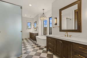 Bathroom with light floors, two vanities, a freestanding tub, a shower stall, and recessed lighting