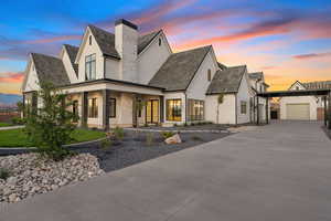 View of front of home with concrete driveway, a garage, covered porch, stucco siding, and a chimney