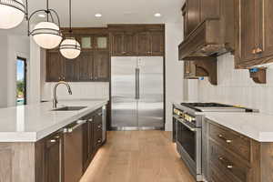 Kitchen featuring high quality appliances, dark brown cabinetry, backsplash, pendant lighting, and recessed lighting