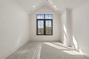 Empty room featuring light colored carpet and vaulted ceiling
