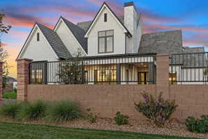 Rear view of property with brick siding, a fenced front yard, a chimney, and roof with shingles