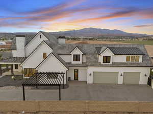 Modern farmhouse style home featuring stucco siding, a chimney, driveway, and a mountain view