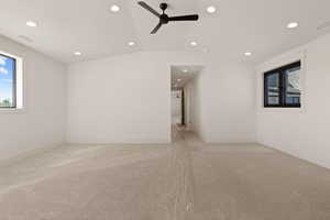 Spare room with healthy amount of natural light, vaulted ceiling, light carpet, ceiling fan, and recessed lighting