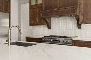 Kitchen featuring premium range hood, tasteful backsplash, glass insert cabinets, and double oven range