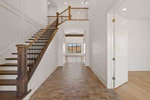 Entryway featuring recessed lighting, a towering ceiling, stairway, and arched walkways