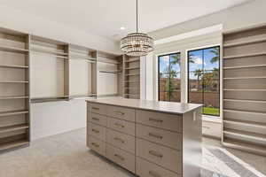 Walk in closet with light carpet and a chandelier