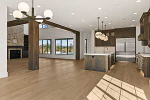 Kitchen featuring premium appliances, open floor plan, light wood-type flooring, dark brown cabinets, and recessed lighting