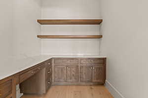 Kitchen with open shelves, light wood-style floors, and light stone countertops