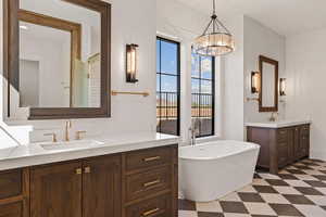 Bathroom with two vanities, a freestanding bath, and dark flooring