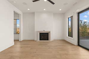 Unfurnished living room with recessed lighting, light wood-style flooring, a glass covered fireplace, and a ceiling fan