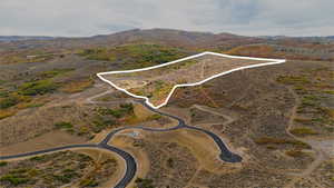 Aerial view of property and surrounding area with property parcel outlined and a mountainous background