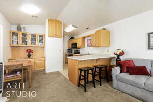 Kitchen featuring a breakfast bar, open floor plan, light countertops, a peninsula, and vaulted ceiling