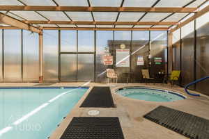 Indoor pool featuring an in-ground hot tub and a patio area