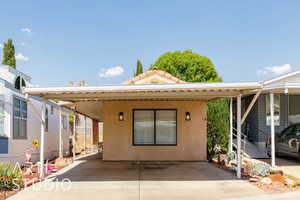 Back of house with stucco siding and a carport